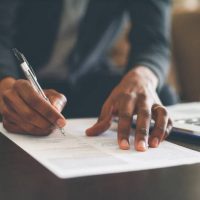 Cropped shot of an unrecognizable man filling out paperwork while doing his budget at home